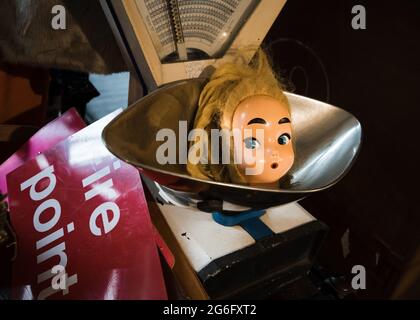 Gruselige Puppen Kopf in Vintage-Waage mit überrascht Blick auf Gesicht angehoben Augenbrauen enthauptete Puppe. Altmodische Schuppen. Seltsames Gesicht und dunkel Stockfoto