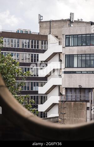 Feuertreppe an der Ecke des alten Betongebäudes aus den 1970er Jahren. Symmetrisches Design an der Außenseite für die Evakuierung der Bewohner im Notfall. Stockfoto