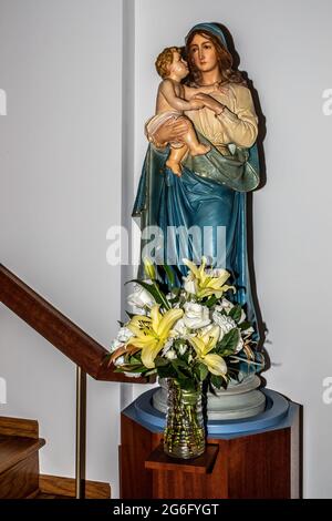 Schöner Blumenstrauß vor der Statue der Maria, die das Jesuskind in der St. Joseph's Catholic Church in Taylors Falls, Minnesota USA, hält. Stockfoto