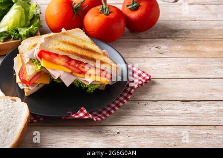 Sandwich mit Tomaten, Salat, Schinken und Käse auf einem Holztisch Stockfoto