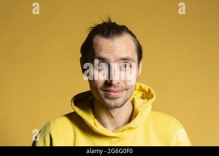 Portrait lächelnder Mann im Kapuzen-Sweatshirt auf gelbem Hintergrund Stockfoto