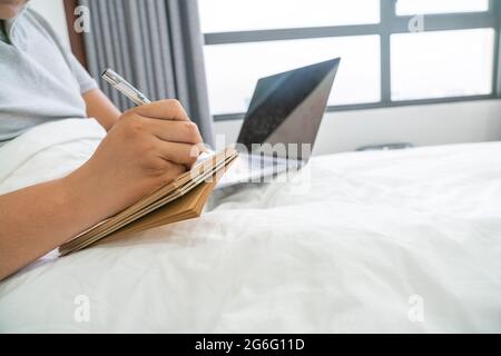 Seitenansicht des Geschäftsmannes, der Notizen auf dem Bett schrieb Stockfoto