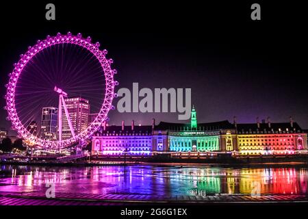 Farbenfrohe Reflexionen von der County Hall, während das London Eye den Himmel erhellt. Stockfoto