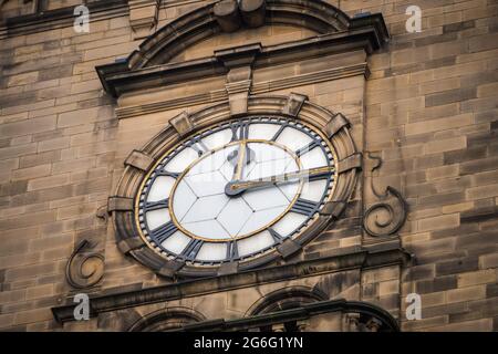 Viertel nach zwölf 12:15 Uhr Zifferblatt zeigt die Zeit mit römischen Ziffern auf historischen alten Steingebäude. Fünfzehn Minuten nach zwölf Uhr. Stockfoto