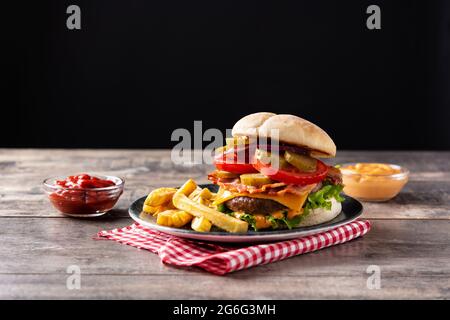 Rinderburger mit Käse, Speck und pommes auf Holztisch Stockfoto