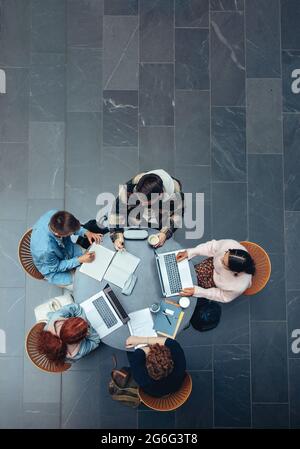High-Angle-Ansicht eines Studenten in Zusammenarbeit mit seinem akademischen Auftrag. Draufsicht von jungen Menschen, die gemeinsam an einem Tisch studieren. Stockfoto
