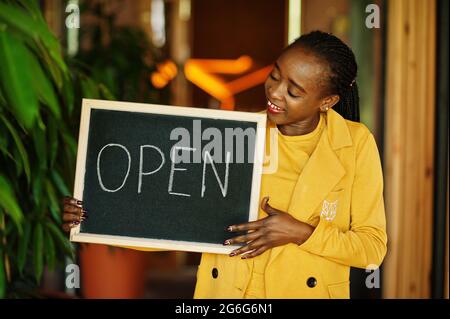 afroamerikanische Frau halten offene Willkommenstafel im modernen Café-Café-Café bereit, Service, Restaurant, Einzelhandelsgeschäft, Kleinunternehmerin. Stockfoto