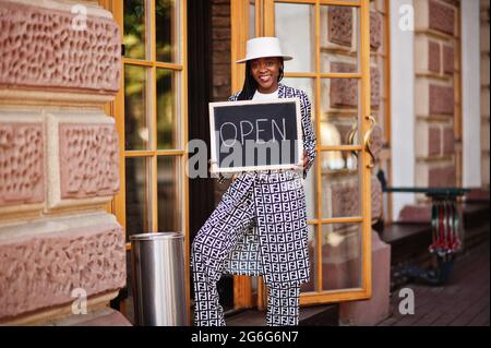 afroamerikanische Frau halten offene Willkommenstafel im modernen Café-Café-Café bereit, Service, Restaurant, Einzelhandelsgeschäft, Kleinunternehmerin. Stockfoto