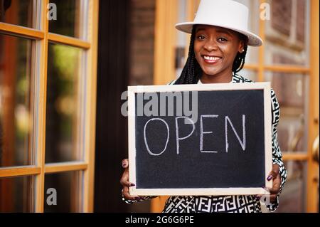 afroamerikanische Frau halten offene Willkommenstafel im modernen Café-Café-Café bereit, Service, Restaurant, Einzelhandelsgeschäft, Kleinunternehmerin. Stockfoto