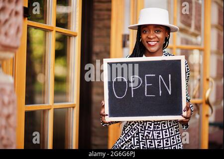 afroamerikanische Frau halten offene Willkommenstafel im modernen Café-Café-Café bereit, Service, Restaurant, Einzelhandelsgeschäft, Kleinunternehmerin. Stockfoto