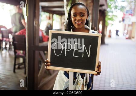 afroamerikanische Frau halten offene Willkommenstafel im modernen Café-Café-Café bereit, Service, Restaurant, Einzelhandelsgeschäft, Kleinunternehmerin. Stockfoto