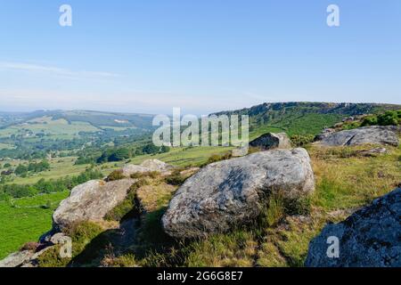 An einem Sommermorgen von hoch auf dem Baslow Edge zwischen den Steinfelsen durch eine trübe Landschaft von Derbyshire Stockfoto