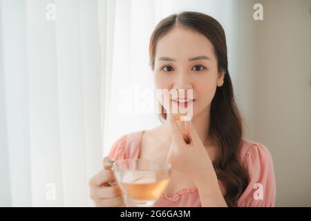 Lächelnde junge Frau, die die Pille isst Stockfoto