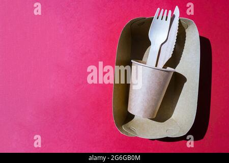 Holzgabeln und Pappbecher mit Tellern auf farbigem Hintergrund. Umweltfreundliches Einweggeschirr. Wird in Fast Food, Restaurants, Imbissbuden und Picknicks verwendet. Nein Stockfoto