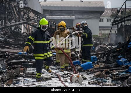 Bang Phli, Thailand. Juli 2021. Thailändische Feuerwehrleute versuchen, einen Brand zu löschen, der durch eine Explosion in einer von einem Brand heimgetragenen Ming Dih Chemical Fabrik im Bezirk Bang Phli, Provinz Samut Prakan, verursacht wurde.bei einer Explosion über Nacht und einem Brand in einer Chemiefabrik wurde eine Person getötet und mehr als 60 weitere verletzt. Am späten Montagnachmittag sendend schwarzer Rauch über Samut Prakans Bang Phli-Gebiet in den Himmel. Feuerwehrleute verwendeten Hubschrauber, darunter auch einige von der Armee, um flammhemmenden Schaum über den brennenden Ming Dih Chemical Co-Anlagenkomplex zu sprühen. Kredit: SOPA Images Limited/Alamy Live Nachrichten Stockfoto