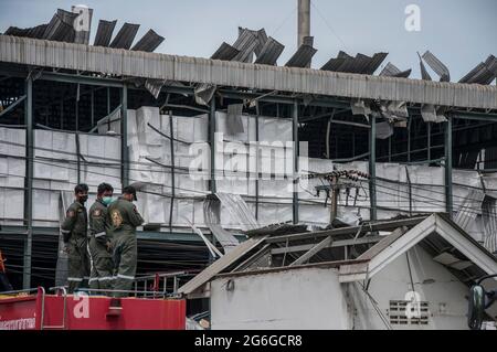 Bang Phli, Thailand. Juli 2021. Freiwillige Helfer stehen neben dem beschädigten Gebäude, das durch eine Explosion in einer von einem Brand heimgetragenen Ming Dih Chemical Fabrik im Bezirk Bang Phli, Provinz Samut Prakan, verursacht wurde.bei einer Explosion über Nacht und einem Brand in einer Chemiefabrik wurde eine Person getötet und mehr als 60 weitere verletzt. Am späten Montagnachmittag sendend schwarzer Rauch über Samut Prakans Bang Phli-Gebiet in den Himmel. Feuerwehrleute verwendeten Hubschrauber, darunter auch einige von der Armee, um flammhemmenden Schaum über den brennenden Ming Dih Chemical Co-Anlagenkomplex zu sprühen. Kredit: SOPA Images Limited/Alamy Live Nachrichten Stockfoto