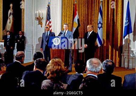 US-Präsident Jimmy Carter, rechts, kündigt am Donnerstag, dem 12. Oktober 1977, im Ostsaal des Weißen Hauses in Washington, DC, Friedensgespräche zwischen der Arabischen Republik Ägypten und dem Staat Israel an. Die Gespräche werden in den Abkommen von Camp David gefordert, die am 17. September 1978 von Präsident Carter, dem ägyptischen Präsidenten Anwar Sadat und Premierminister Menachem Begin von Israel unterzeichnet wurden. Links steht der israelische Außenminister Moshe Dayan und der ägyptische Verteidigungsminister Kamel Hassan Ali, rechts.Quelle: Benjamin E. 'Gene' Forte/CNP/Sipa USA Stockfoto