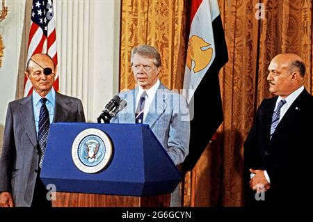 US-Präsident Jimmy Carter, rechts, kündigt am Donnerstag, dem 12. Oktober 1977, im Ostsaal des Weißen Hauses in Washington, DC, Friedensgespräche zwischen der Arabischen Republik Ägypten und dem Staat Israel an. Die Gespräche werden in den Abkommen von Camp David gefordert, die am 17. September 1978 von Präsident Carter, dem ägyptischen Präsidenten Anwar Sadat und Premierminister Menachem Begin von Israel unterzeichnet wurden. Links steht der israelische Außenminister Moshe Dayan und der ägyptische Verteidigungsminister Kamel Hassan Ali, rechts.Quelle: Benjamin E. 'Gene' Forte/CNP/Sipa USA Stockfoto