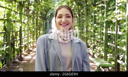 Junge muslimische Frau im Kopftuch lächelt im Park Stockfoto