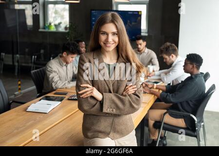 Junge Geschäftsfrau sitzt auf dem Schreibtisch und posiert Stockfoto
