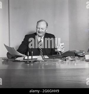 1970s, historischer, geeigneter Geschäftsführer, der mit einem handgehaltenen Diktat- oder Tonaufnahmegerät an seinem Schreibtisch sitzt, England, Großbritannien. Stockfoto