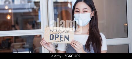 Porträt des asiatischen Ladenbesitzers mit offenem Schild nach Entsperrung Quarantäne, weil sie Coronavirus-Impfstoff erhalten und Laden eröffnen können Stockfoto