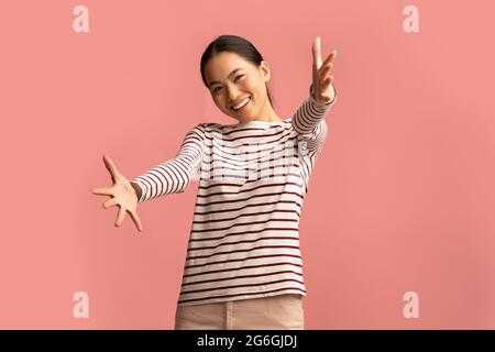 Gebt Mir Einen Hug. Porträt Einer Positiven Asiatischen Frau, Die Die Hände Bei Der Kamera Streckt Stockfoto
