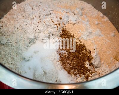 Roggenmehl, Salz, gemahlener Kreuzkümmel und getrocknete Hefe in einer Edelstahlschüssel - Basis für Brotteig - selektiver Fokus Stockfoto