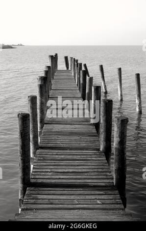 Am Meer, schöne Aussicht auf einen hölzernen Pier, Schwarz-Weiß-Fotografie. Hölzerner Pier, der zum Meer oder zum See, zur Promenade führt. Neusiedler See. Stockfoto