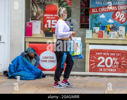 Preston, Lancashire. UK Wetter 6. Juli 2021 Obdachloser Mann in schlechter Gesundheit sitzt auf dem Bürgersteig vor dem Kartengeschäft Verkauf von Weihnachtskarten. Menschen, die Obdachlosigkeit erfahren, insbesondere Menschen, die rauh schlafen, sind während der Pandemie stark gefährdet. Bei ihnen besteht eine dreimal höhere Wahrscheinlichkeit für eine chronische Erkrankung, einschließlich Atemwegserkrankungen wie COPD. Kredit; MediaWorldImages/AlamyLiveNews Stockfoto