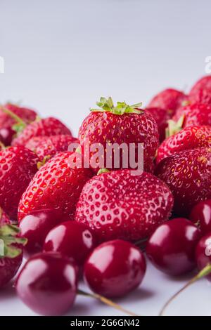 Nahaufnahme aus vertikalen Aufnahmen mit roten Kirschen und Erdbeeren. Stockfoto