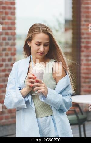 Eine Frauenhand hält einen erfrischenden Cocktail in einem Glas mit einer Tube. Stockfoto