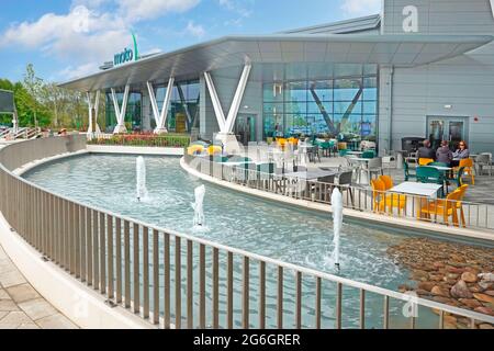 Wasserspiel Landschaftsbau Brunnen Menschen im Freien Restaurant Tische Moderne Moto Service Station M6 Autobahn Rugby Junction Warwickshire England Großbritannien Stockfoto