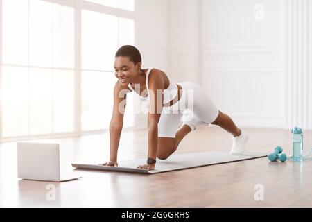 Fröhliche Afro-Frau Beim Training Von Cross Body Mountain Kletterern Stockfoto