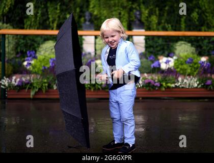 Ein junger Fan schützt sich am achten Tag von Wimbledon vor Regen im All England Lawn Tennis and Croquet Club, Wimbledon. Bilddatum: Dienstag, 6. Juli 2021. Stockfoto