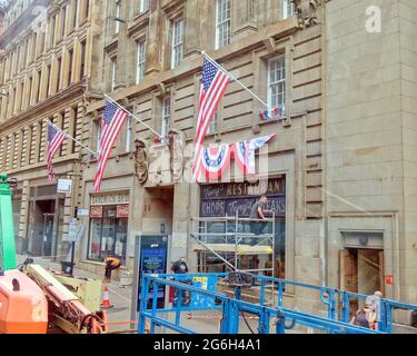 Glasgow, Schottland, Großbritannien, 6. Juli 2021. UK Weather: Letzte Vorbereitungen für die Dreharbeiten in der St vincent Street für die Dreharbeiten zum Mystery Blockbuster, der ein Vermögen gekostet hat, den Standort im Stadtzentrum entlang seiner Länge vorzubereiten und die Kameras morgen einzuziehen. Amerikanische Flaggen und Präsidentenanstacheln auf der New yorker Architektur mit der Umwandlung von lokalen Geschäften in manhattan hat zu Spekulationen über den indiana jones-Film geführt, aber das neueste Gerücht ist, dass das neue Fledermaus-Handy aufgrund der Größe von die Länge der Straße hochlaufen wird Die Lage. Quelle: Gerard Ferry/Alamy Live News Stockfoto