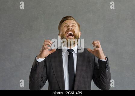 Verrückter, wütender Geschäftsmann, der mit aggressivem Ausdruck aufblickte und die Hände hob. Stockfoto