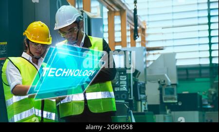 Asiatische Ingenieure männlich weiblich in der Industrie tragen Harthüte in der Industrie Fertigung Fabrik mechanische Anzeige Schnittstelle Arm Roboter Fertigung indust Stockfoto