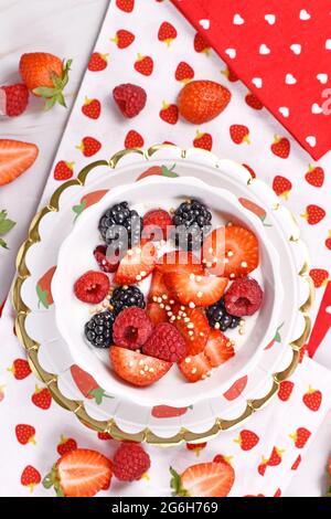Draufsicht auf eine Joghurt-Schüssel mit Erdbeer-, Himbeer- und Brombeerfrüchten und gepufftem Quinoa Stockfoto