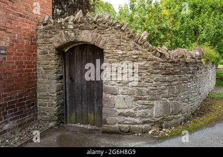 Alte Holztür an einer Steinmauer in der Nähe eines Gartens Stockfoto