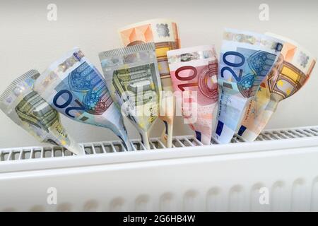 Euro-Banknoten, die aus einem Heizkörper kommen und Wärme als Geld symbolisieren. Stockfoto