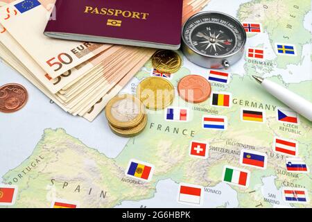 Eine Anordnung von Euro-Scheinen, Münzen, Reisepass und Kompass auf Schiefer. Stockfoto