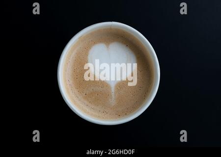 Oberhalb von Cappuccino. Kaffee zum Mitnehmen in Thermobecher aus Karton auf schwarzer Oberfläche. Draufsicht Stockfoto