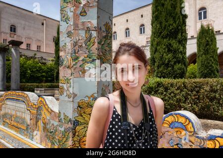 Junge Touristen besuchen die Gärten einer alten christlichen Basilika. Das Mädchen mit der Kamera ist glücklich und lächelt. Stockfoto