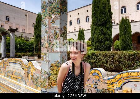 Junge Touristen besuchen die Gärten einer alten christlichen Basilika. Das Mädchen mit der Kamera ist glücklich und lächelt. Stockfoto