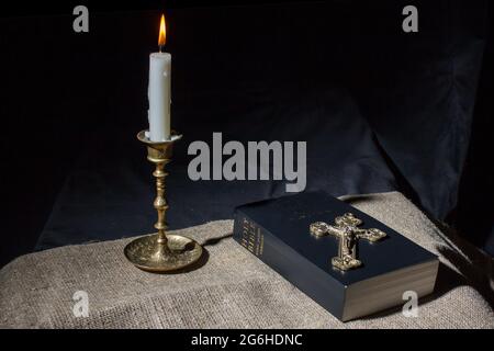 Bronzekreuz, brennende Kerze und bibel auf der tablee-Innenaufnahme Stockfoto
