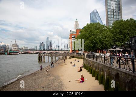 Menschen, die das sonnige Wetter am Thames Beach am Südufer des Flusses genießen. Stockfoto