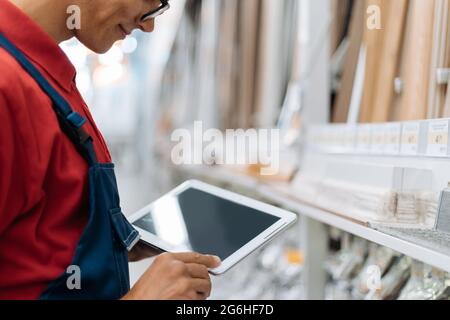 Berater des Bodenbelags-Stores mit einem digitalen Tablet arbeitet im Verkaufsbereich. Stockfoto