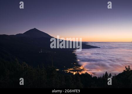 Landschaft mit Vulkan Pico de Teide über Wolken bei schöner Dämmerung. Stadt La Orotava ​in Teneriffa. Kanarische Inseln, Spanien. Stockfoto