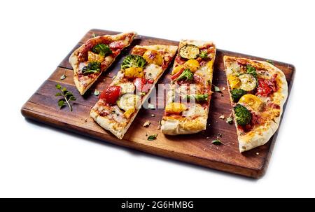 Von oben von leckeren vegetarischen Pizza mit verschiedenen Gemüse auf Holz Schneidebrett auf weißem isolierten Hintergrund platziert Stockfoto